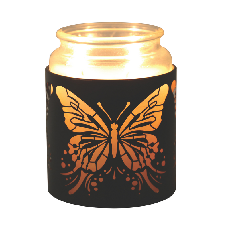 Lit candle inside a jar with a black butterfly cutout design. The warm glow highlights the intricate wings, creating a cozy and serene atmosphere