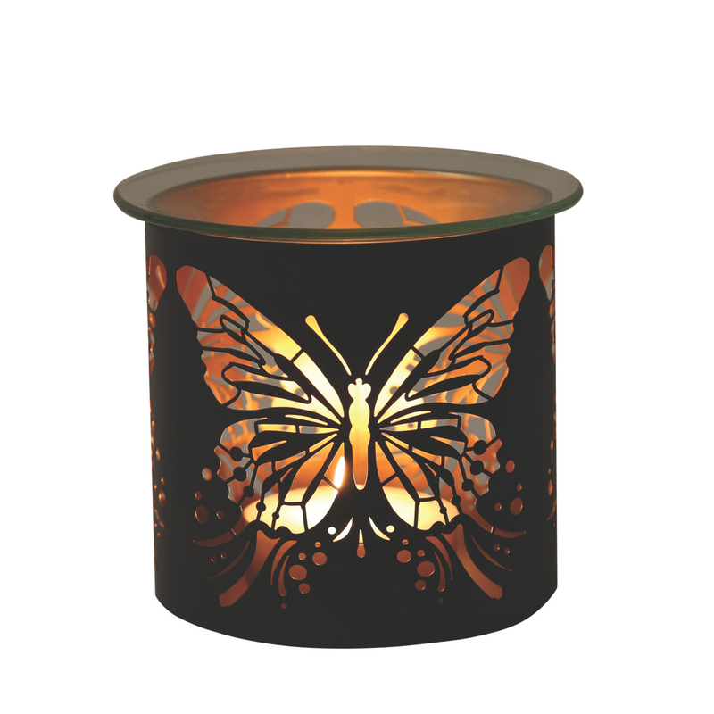 A black cylindrical wax melt warmer with a butterfly cutout design glows warmly, casting an amber light. The intricate patterns create a calm, cozy ambiance.