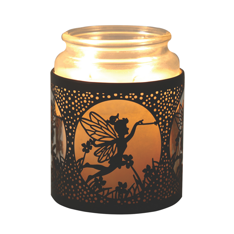 Lit candle in a glass jar with a decorative black metal holder. The holder features a fairy silhouette among flowers, casting a whimsical, warm glow.