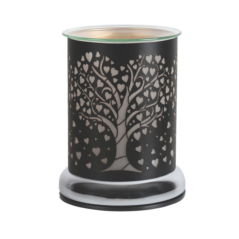 Elegant electric wax melt warmer with a cutout tree and heart design on black metal. Glass top and chrome shiny base, conveying warmth and sophistication.