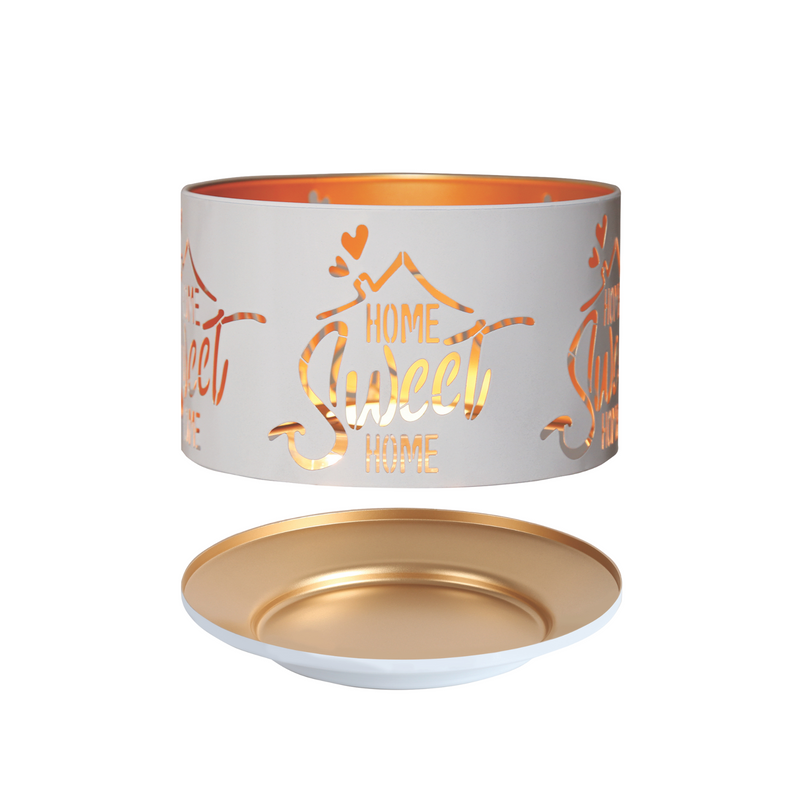 Round white candle shade with "Home Sweet Home" cutouts, revealing a warm gold glow inside. Accompanied by a matching gold and white candle tray.