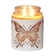 Lit candle in a glass jar with a white butterfly design on the cover, glowing warmly. The ambiance is cozy and tranquil, suggesting relaxation.
