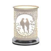 A decorative white electric wax melt warmer features two silhouetted birds on a branch, enclosed in a circular frame. Warm light glows, creating a cosy, romantic ambiance.