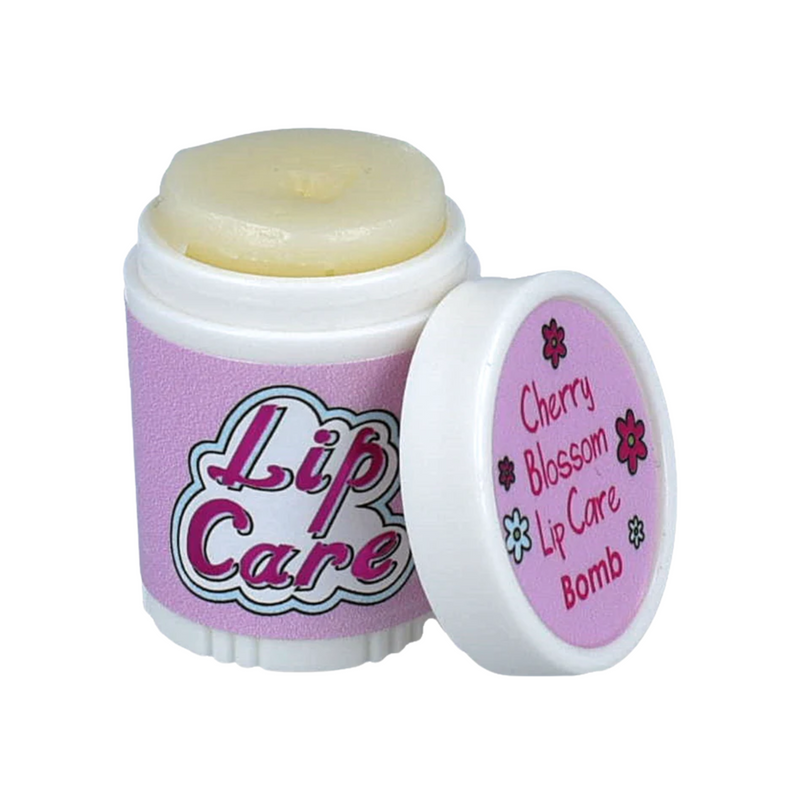 Lip care product in a container featuring a twist-off cap. The container is predominantly pink with the words "Lip Care" in bold, colorful lettering on the front. The cap is slightly open, revealing a pale yellow lip balm inside. Next to it, a smaller lid displays the text "Cherry Blossom Lip Care Bomb" along with a floral design. The overall design suggests a playful and soothing lip care product.