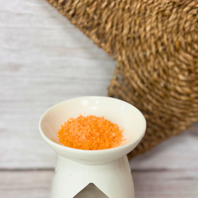 Image of Little House of Fragrance Aventos Fragrance Scent Sizzlers which are orange being used in a tealight warmer