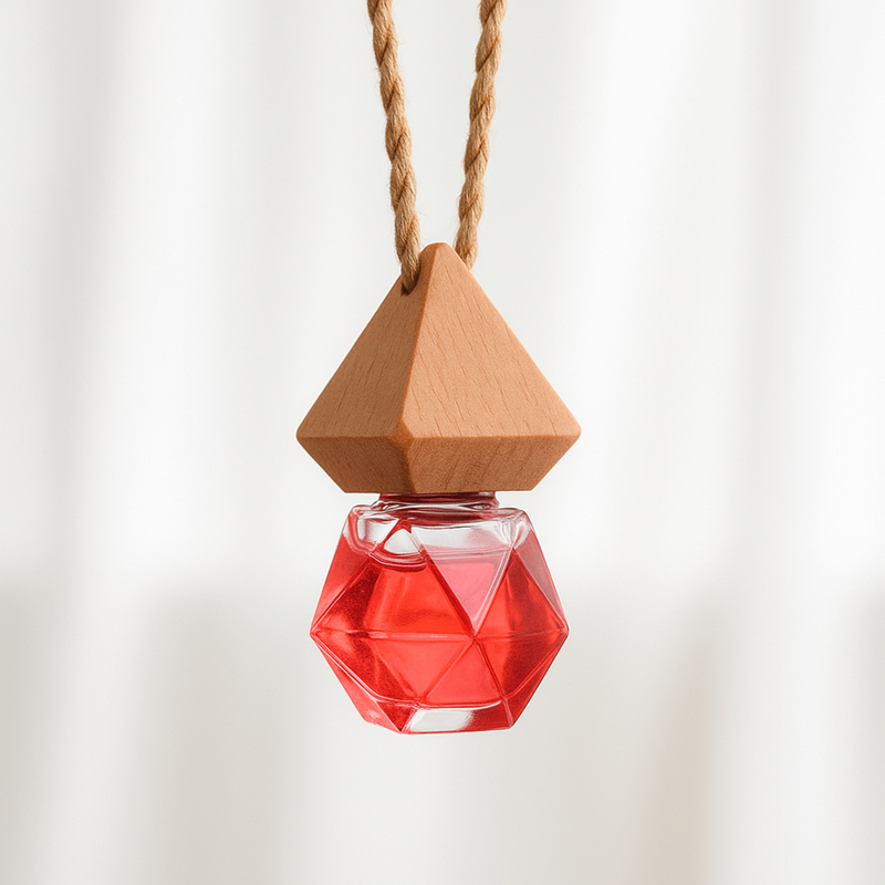 A geometric red glass bottle car fragrance diffuser  hangs from a textured rope, topped with a wooden pyramid lid. The background is softly blurred, creating a minimalist feel.