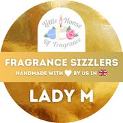 A gold circular label with a logo showing a candle, flowers, and text "Little House of Fragrance." Text reads "Fragrance Sizzlers, Handmade with ♥ by us in 🇬🇧, Lady M."