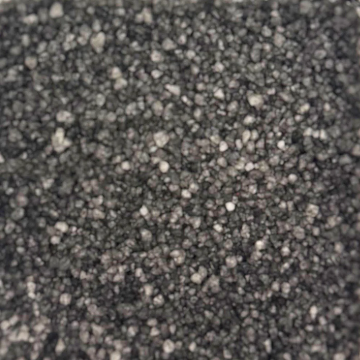 Close-up view of coarse black fragrance scent sizzlers  with a rough texture, resembling gravel or charcoal, filling the image. The tone is neutral and industrial.