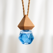 Hanging geometric blue glass bottle with wooden cap, suspended by a twisted rope against a soft beige background. Minimalist and elegant design.