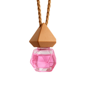 Geometric pink glass bottle with wooden top on a braided string. The faceted design reflects light, suggesting a playful, elegant tone.