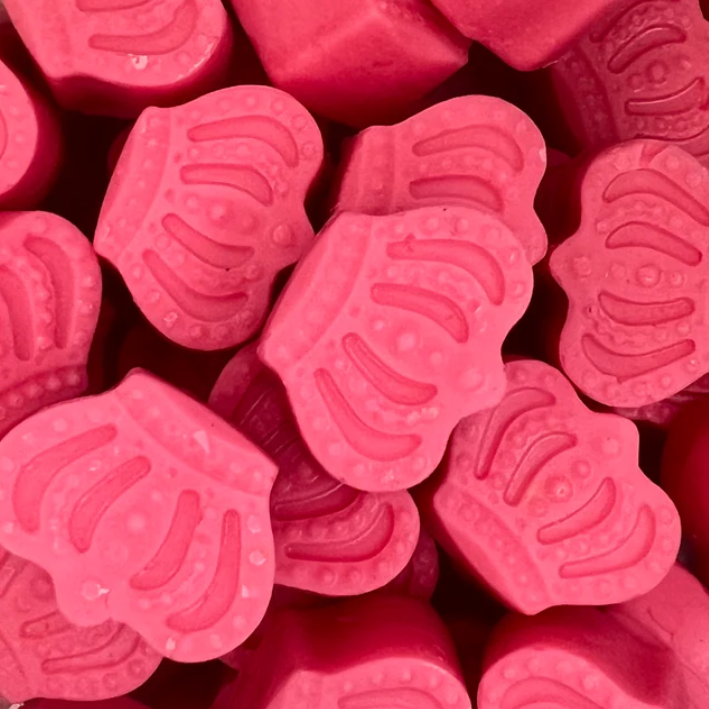 Bright pink wax melts shaped like crowns, intricately designed and packed closely together. The scene is playful, with a whimsical, sweet tone.