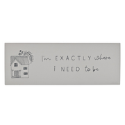 Wooden block sign with a simple sketch of a house and plants on the left. The handwritten message reads, "I'm exactly where I need to be."