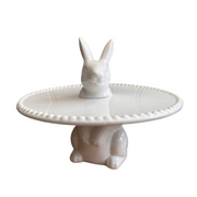 White ceramic cake stand featuring a rabbit motif, with a rabbit head on top and body as the base. The design is clean and whimsical, perfect Spring cake stand.