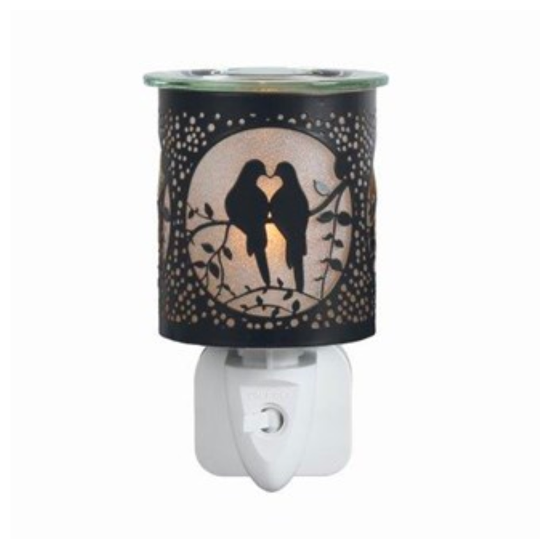 Electric wax melt warmer with a warm glow, featuring a romantic silhouette of two birds on a branch. Decorative cutouts create a cozy, intimate ambiance.